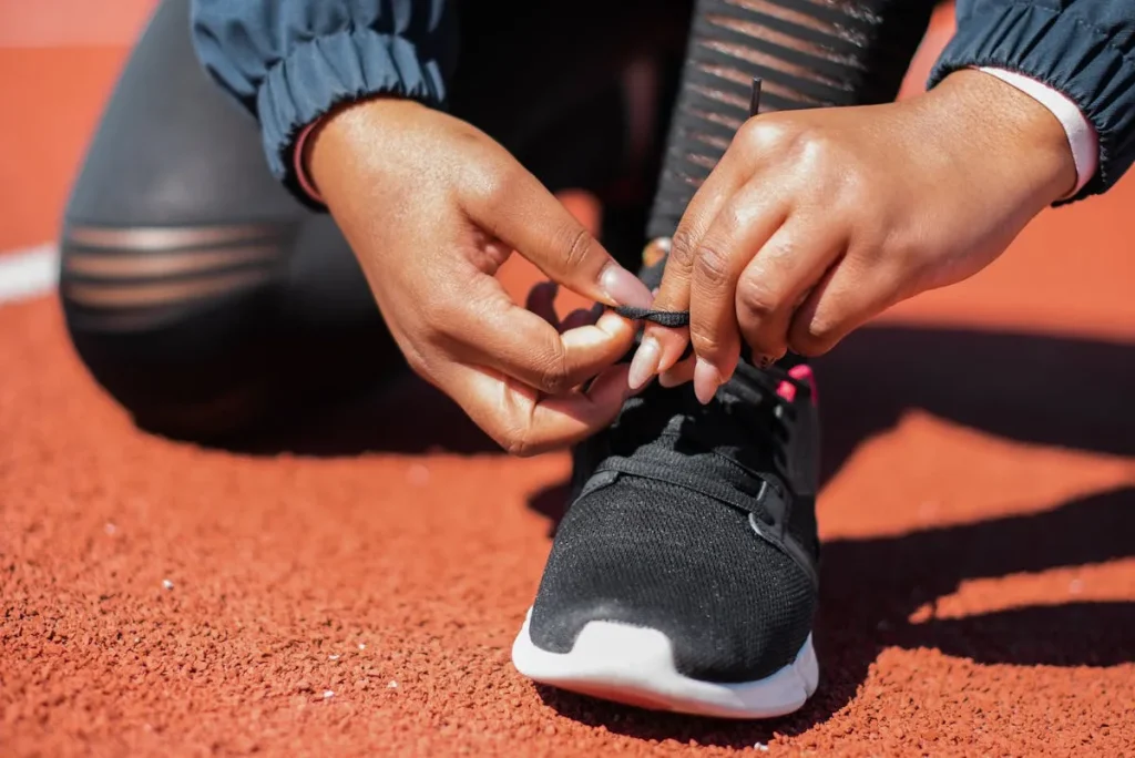 Close-up of runner tying laces on running shoes on a track — how to choose the right running shoes