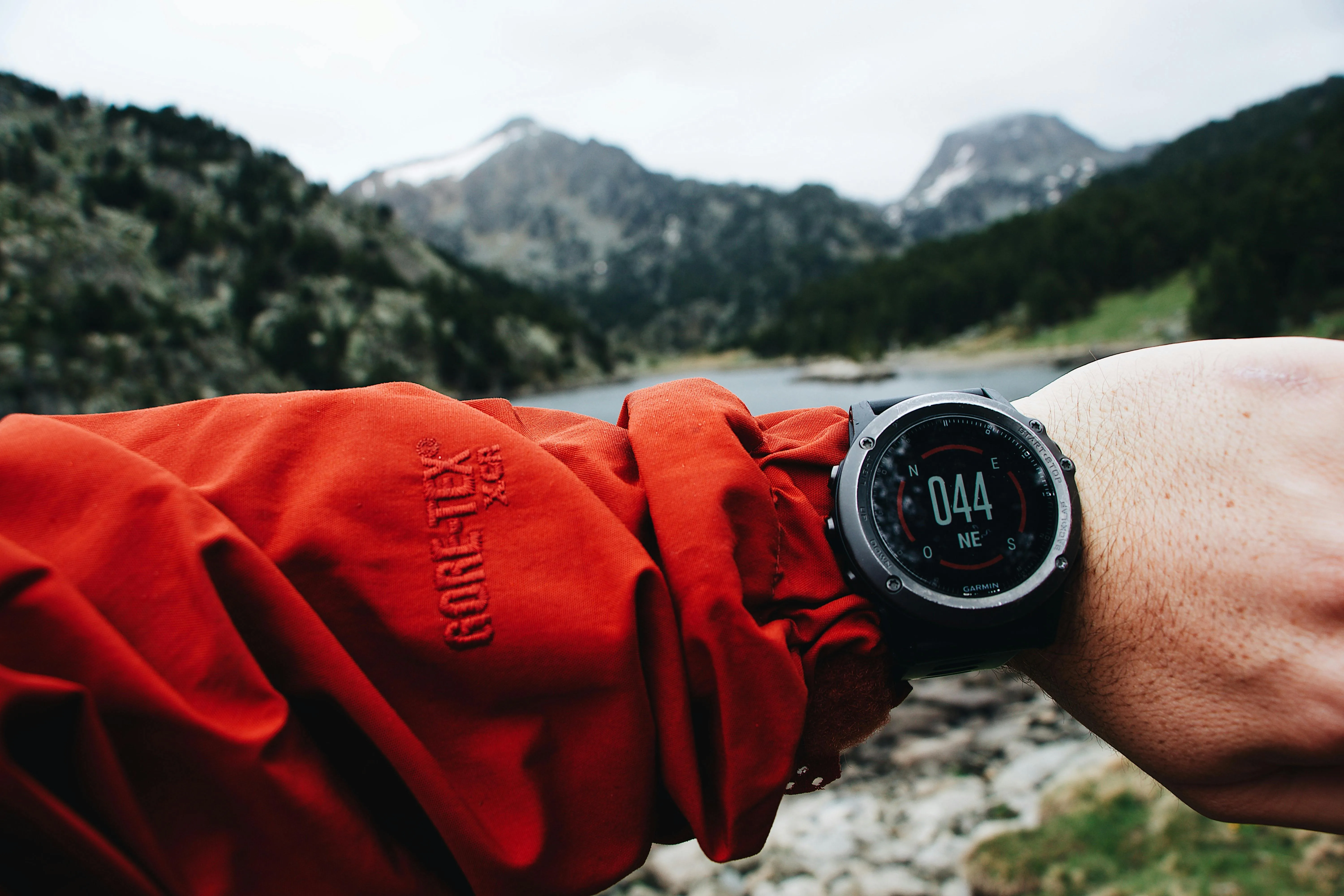 GPS running watch on wrist displaying compass during outdoor trail run