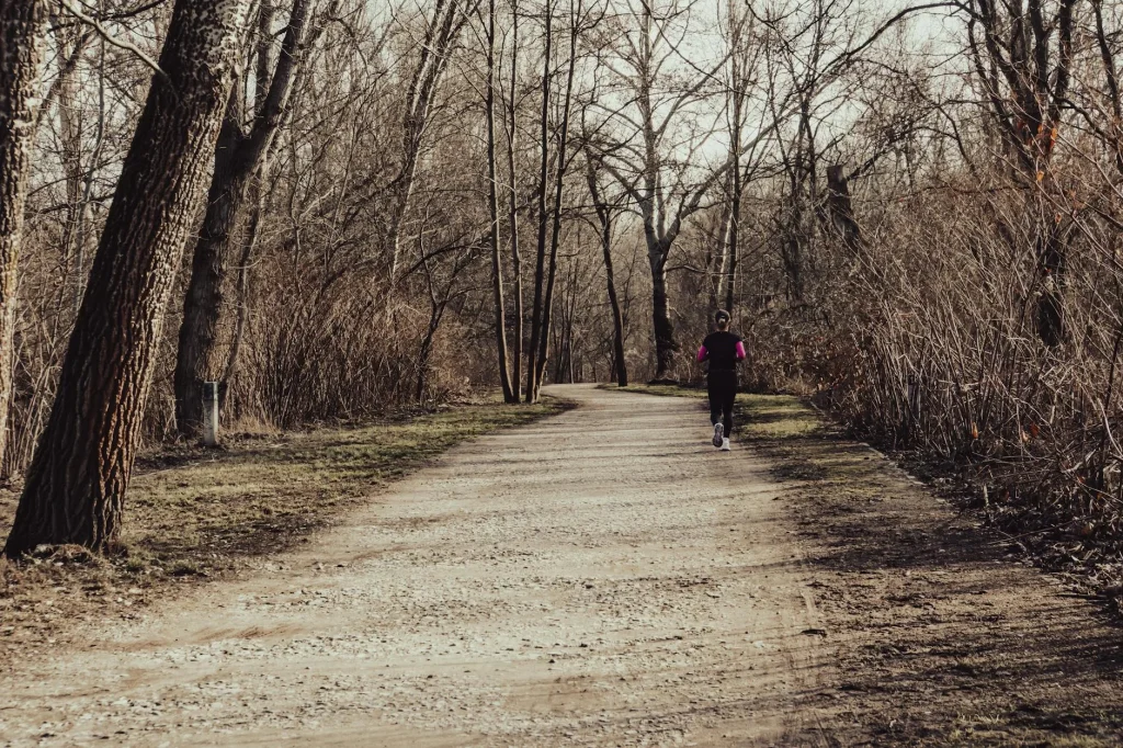 Runner jogging through an autumn park with fallen leaves