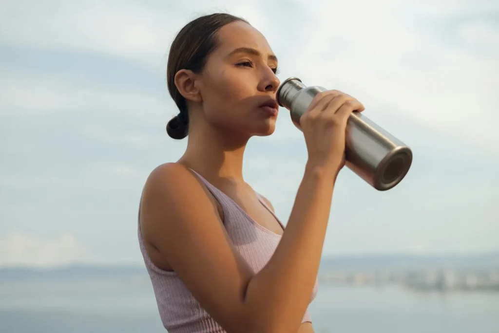 Runner drinking from a water bottle after exercise outdoors