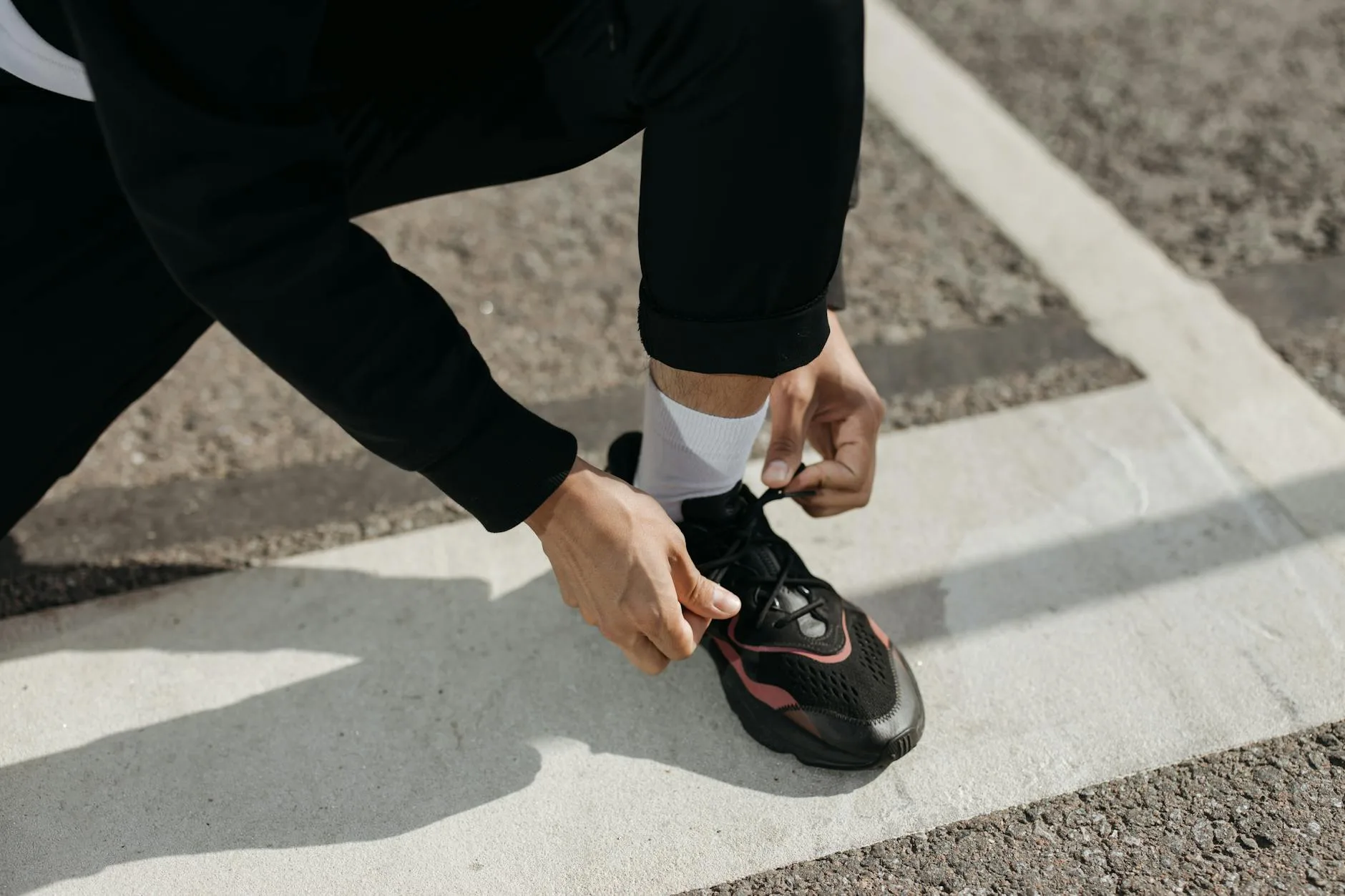 Runner tying running shoes with quality socks visible on a road
