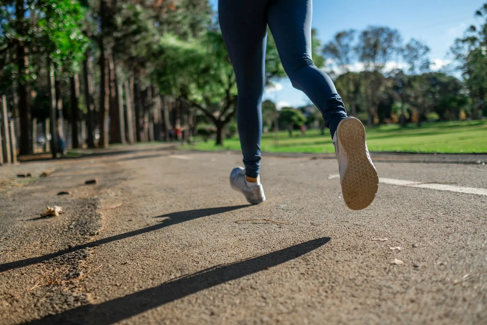Runner mid-stride on a park path showing running shoe soles