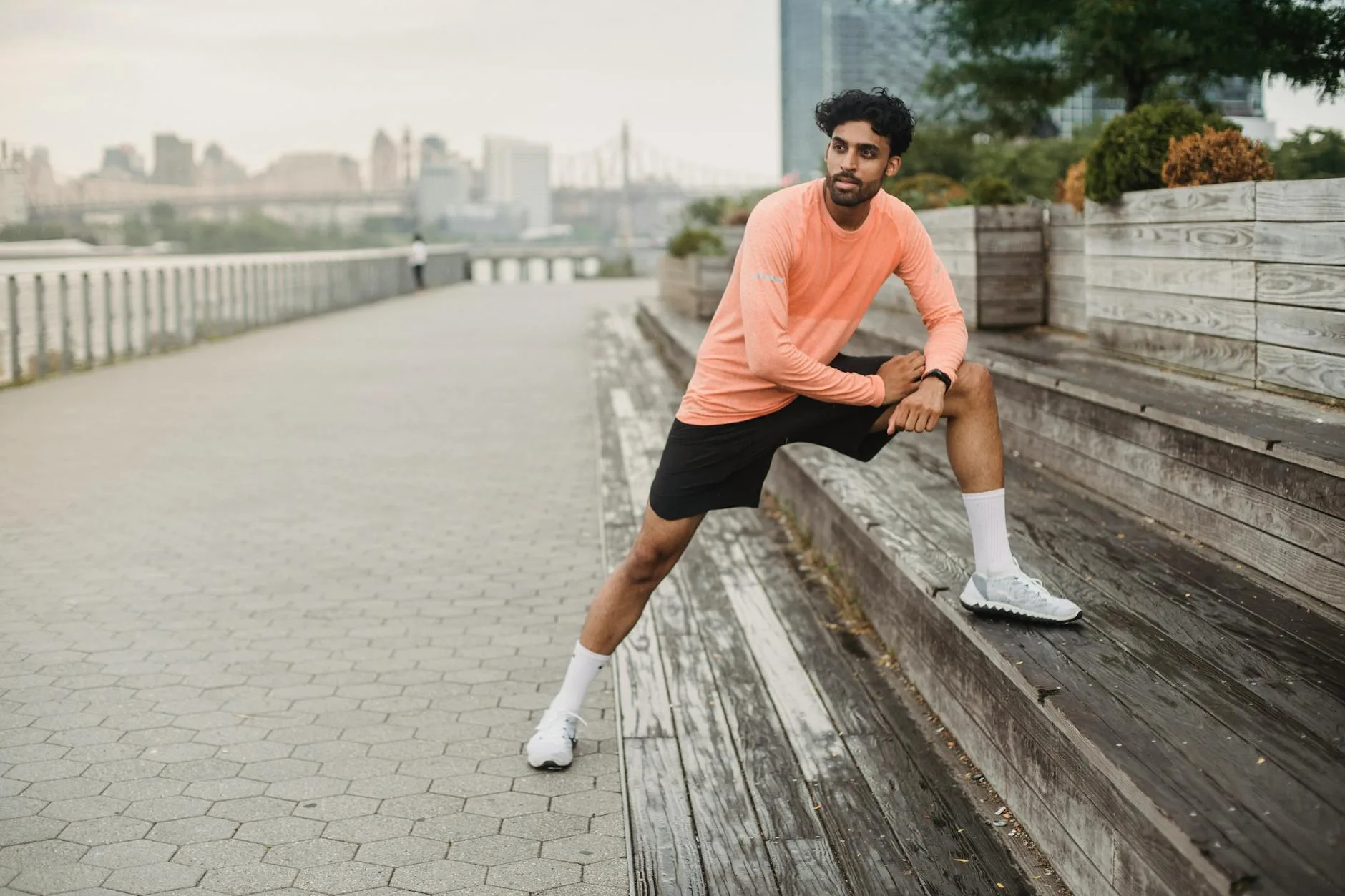 Runner stretching before a run in a park wearing a fitness watch