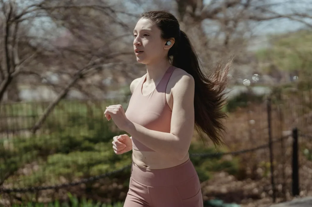 Runner wearing sport earbuds while jogging on a road