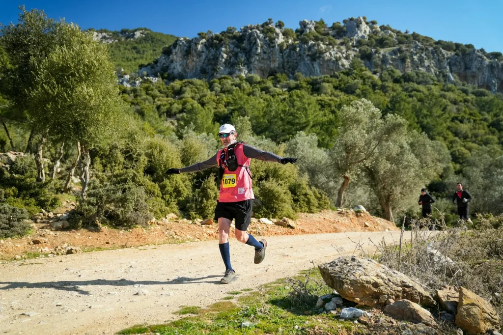 Trail runner wearing a hydration vest on a mountain path