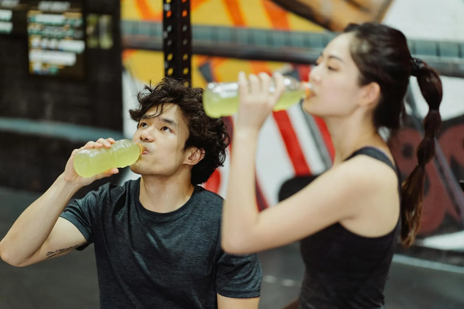 Two athletes drinking sports drinks after a gym workout