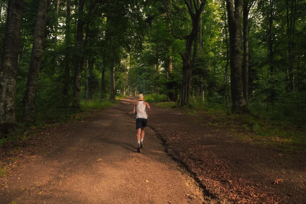 Runner on a muddy trail path through a forest