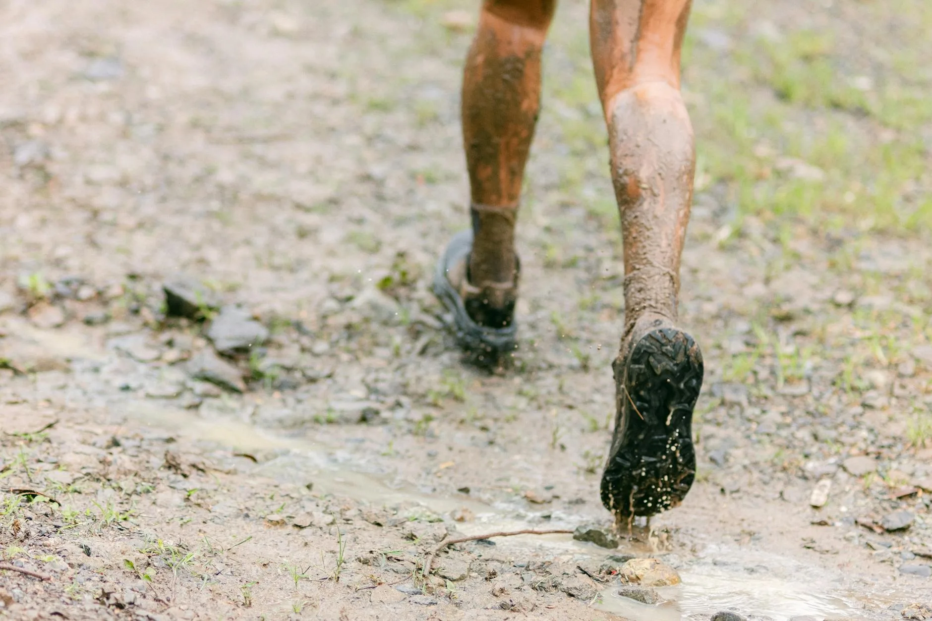 Close-up of trail running shoe gripping muddy ground