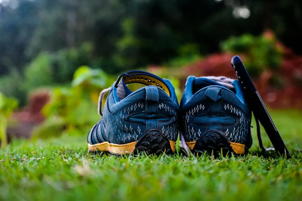 Worn running shoes on grass showing scuffed soles from behind